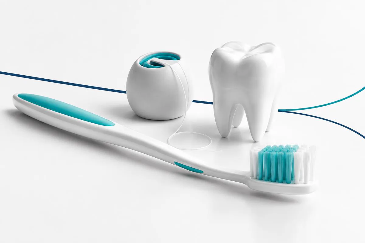 Brosse à dents, fil dentaire et dent en céramique blanche